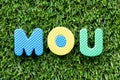 Color letter in word MOU Abbreviation of memorandum of understanding on artificial green grass background