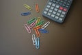 Color clips of different colors with a gray calculator on a brown matte background Royalty Free Stock Photo