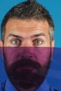 Color concept. Bearded man hiding her face behind colored glass. Serious bearded man partially closed by glass. Vivid