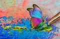 color concept. colorful tropical morpho butterfly on an artist\'s palette with a brush and strokes of oil paint Royalty Free Stock Photo