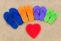 Color flip flops and heart on sand