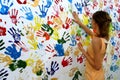 Color handprints on a white wall and young woman who makes them Royalty Free Stock Photo