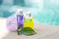 Color massage oil in clear glass bottle with fresh green leaf and purple paper umbrella over blurred blue water background Royalty Free Stock Photo