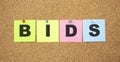 Color notes with letters pinned on a board. Word BIDS Royalty Free Stock Photo