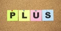 Color notes with letters pinned on a board. Word PLUS. Royalty Free Stock Photo