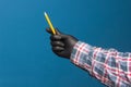 Color pencil in the hand of a person with black glove