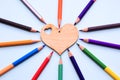 Color pencils in arrange in color wheel colors around wooden heart on blue background. Royalty Free Stock Photo