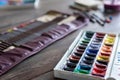 Color pencils, brushes and watercolor paints on wooden table. art painter accessories. front light , selective focus Royalty Free Stock Photo