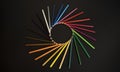 Color pencils isolated on the black background forming a circle. Rays of color pencils