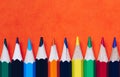 Color pencils isolated on orange background. Close up of colored rainbow pencils for drawing, concept of preparing for school and Royalty Free Stock Photo