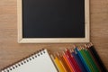Color pencils with notebook and blackboard Royalty Free Stock Photo
