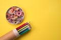 Color pencils in paper packaging tube and shavings on bright yellow background, mockup and copyspace for text. Back to school or Royalty Free Stock Photo