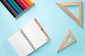 Horizontal minimalistic close-up flat lay composition with Clear sheet note book, two wooden rulers triangles and colour pencils