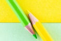 Color pencils on yellow and green color papers arranged diagonally Royalty Free Stock Photo