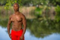Color photo of a handsome young man posing shirtless in the park