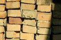 A color photograph of the construction of a brick wall standing in a row on a sunny day.