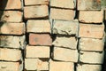 A color photograph of the construction of a brick wall standing in a row on a sunny day.