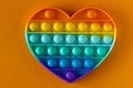 Color pop it antistress toy for children. rainbow heart shaped on orange background . Pop it toy