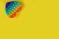 Color pop it antistress toy for children. rainbow heart shaped on yellow background . Pop it toy.Copy space