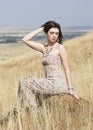 Color portrait of bohemian woman seated in golden field of grass