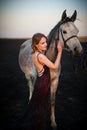 Color portrtait of beautiful woman in evening dress posing next to horse. Royalty Free Stock Photo