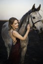 Color portrtait of beautiful woman in evening dress posing next to horse. Royalty Free Stock Photo