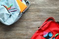 Color rucksacks with school stationery on wooden background