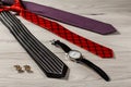 Color silk neckties, watch, cuff-links on a gray wooden background