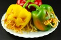 Color stuffed peppers with scary cutout faces, halloween party f