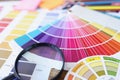 Color swatches and magnifying glass lying on table closeup