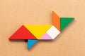 Color tangram in fish or shark shape on wood bacground