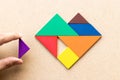 Color tangram in heart shape that wait triangle piece to fulfill shape on wood background Royalty Free Stock Photo