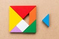 Color tangram in square shape that wait to fulfill on wood background