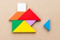 Color tangram that wait triangle piece to complete home shape on wood background Concept about for build dream house, Royalty Free Stock Photo