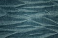 Color toned close up picture of wrinkly jeans fabric background.