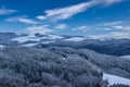 Winter panorama of a snowy countryside with forest and hills, farm buildings, fields and valleys Royalty Free Stock Photo