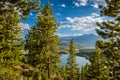 Colorado lake with green pines in the foreground, mountains in the background and white clouds on blue sky. Royalty Free Stock Photo