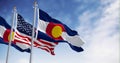 The Colorado state flag waving with the national flag of the US on a clear day