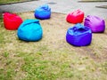 Colored armchair bags lie on the lawn with trampled grass in the park