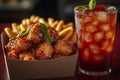 On a colored background, a paper box of fried popcorn chicken and a plastic cola cup are displayed together Royalty Free Stock Photo