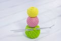 Colored balls for knitting and knitting needles lie on a white wooden background. copyspace. creation. green, yellow and pink thre Royalty Free Stock Photo