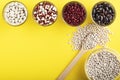 Colored bean in glass jars and wooden spoon of white bean on a yellow background. Image with copy space