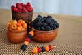 Colored berries of red, yellow and black raspberries or blackberries in earthenware Royalty Free Stock Photo