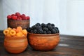 Colored berries of red, yellow and black raspberries or blackberries in earthenware on a  table Royalty Free Stock Photo