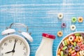 Colored breakfast cereals in a bowl, alarm clock and bottle of milk, close up. Royalty Free Stock Photo