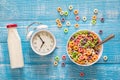 Colored breakfast cereals in a bowl, white alarm clock and bottle of milk. Royalty Free Stock Photo