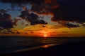 Colored bright orange red yellow pink sunset with clouds on beach sea, dark evening Royalty Free Stock Photo