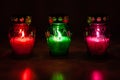 Colored burning votive candles in the dark