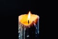 Colored candle with drips of wax burns in the dark