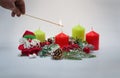 Colored candles lit with burning rushlight, a toy Santa Claus and a Christmas wreath with fir cones Royalty Free Stock Photo